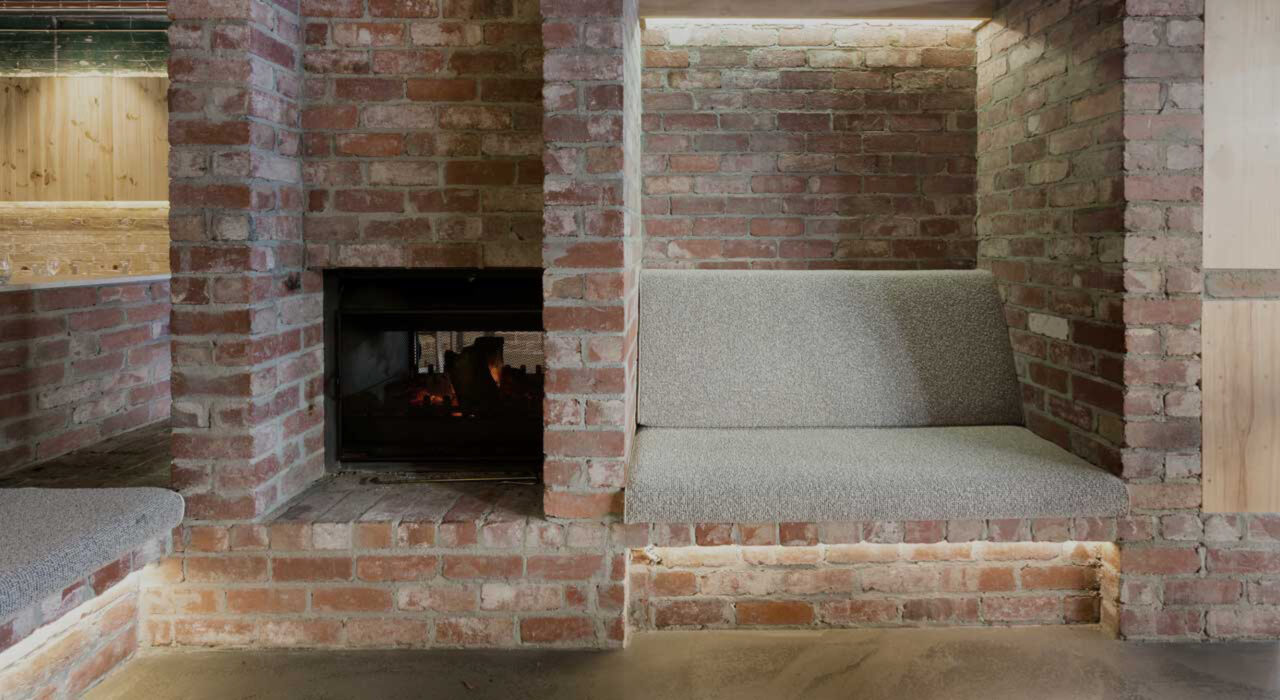 small couch in a brick room upholstered with grey textile