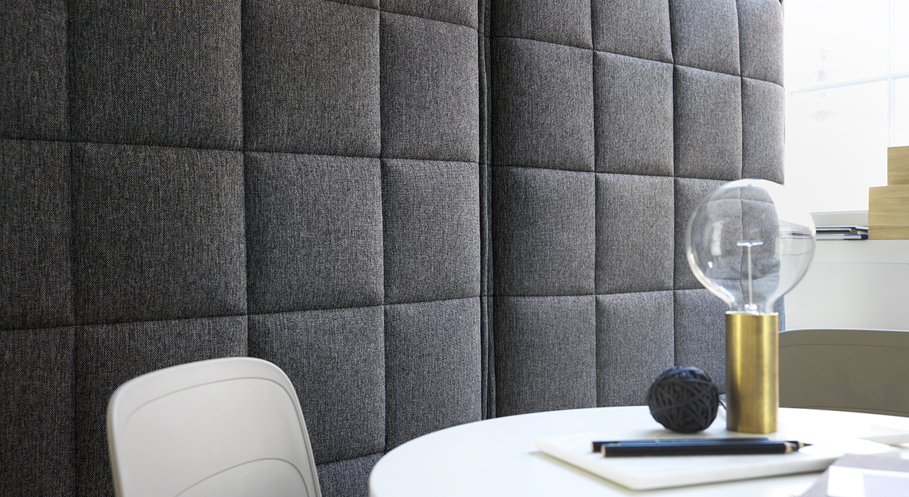 detail of grey upholstered acoustic floor screen behind white table