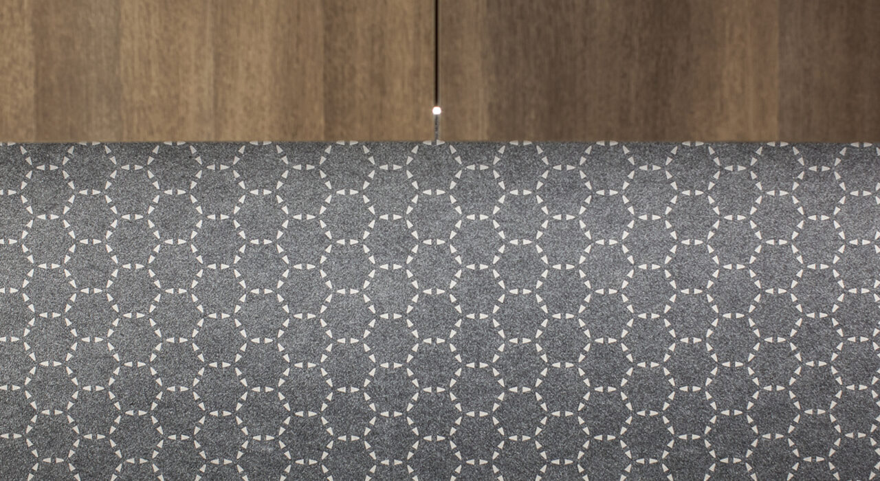 edge of a grey felt faced panel with off white circular design pattern