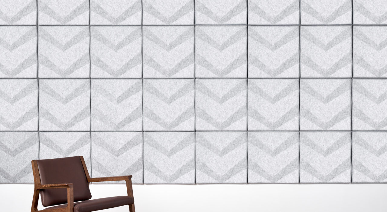 light grey acoustic wall tiles with a chevron pattern behind wooden chair
