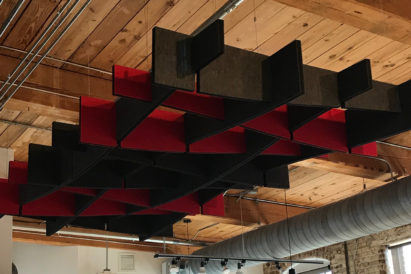 red and black acoustic baffles suspended from a wooden ceiling