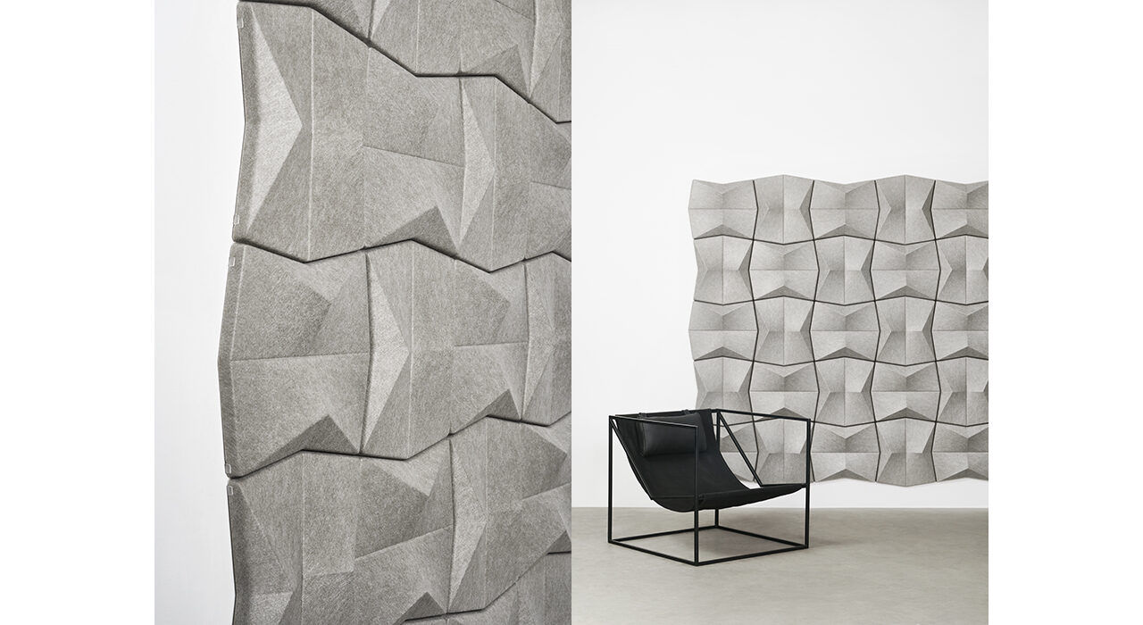 detail of grey sound absorbing tiles on white wall with black chair in foreground
