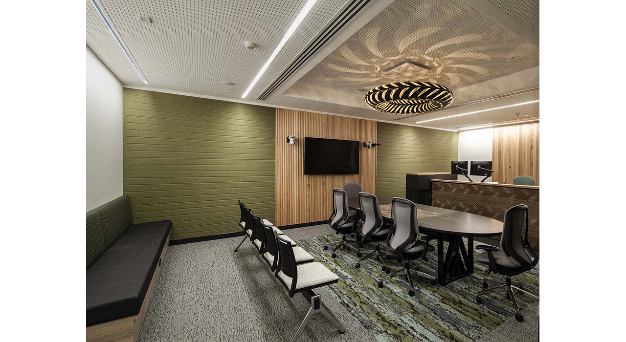 soft green fabric on conference room wall with white green and dark grey upholstered chairs and booths