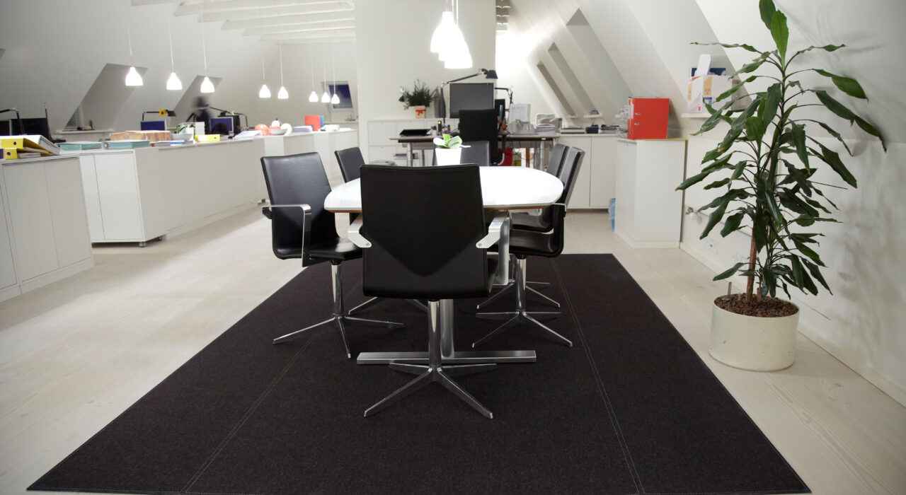 rectangular wool felt rug with light stitching pattern in office under desk and chairs