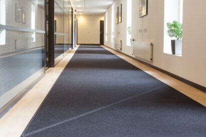 dark grey felt rug with light stitching in a long corridor